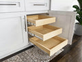 Maple roll-out trays in an open white shaker base cabinet